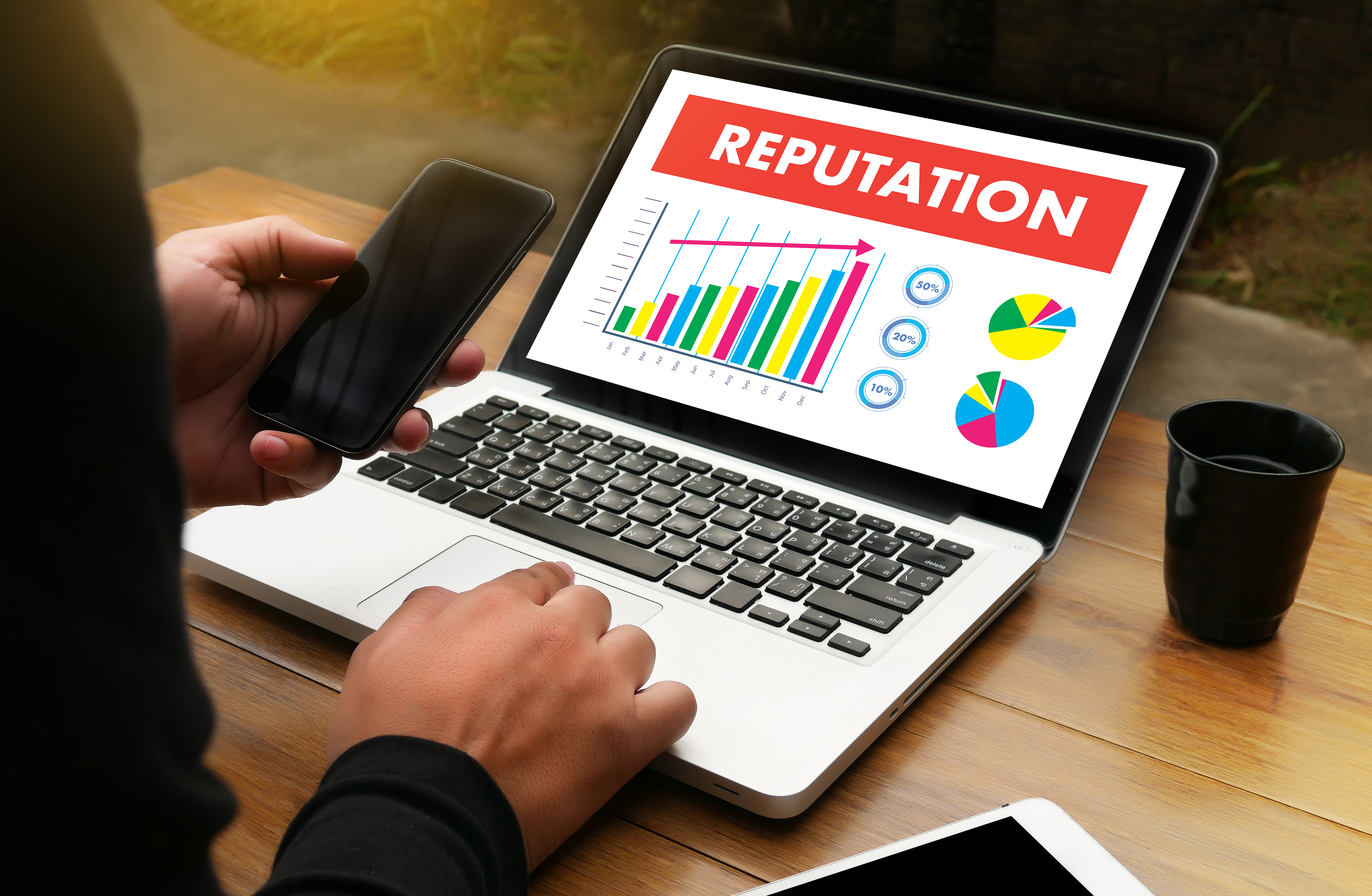 Work desk that has a monitor with a dashboard displaying an increase in all metrics with a header 'reputation' 